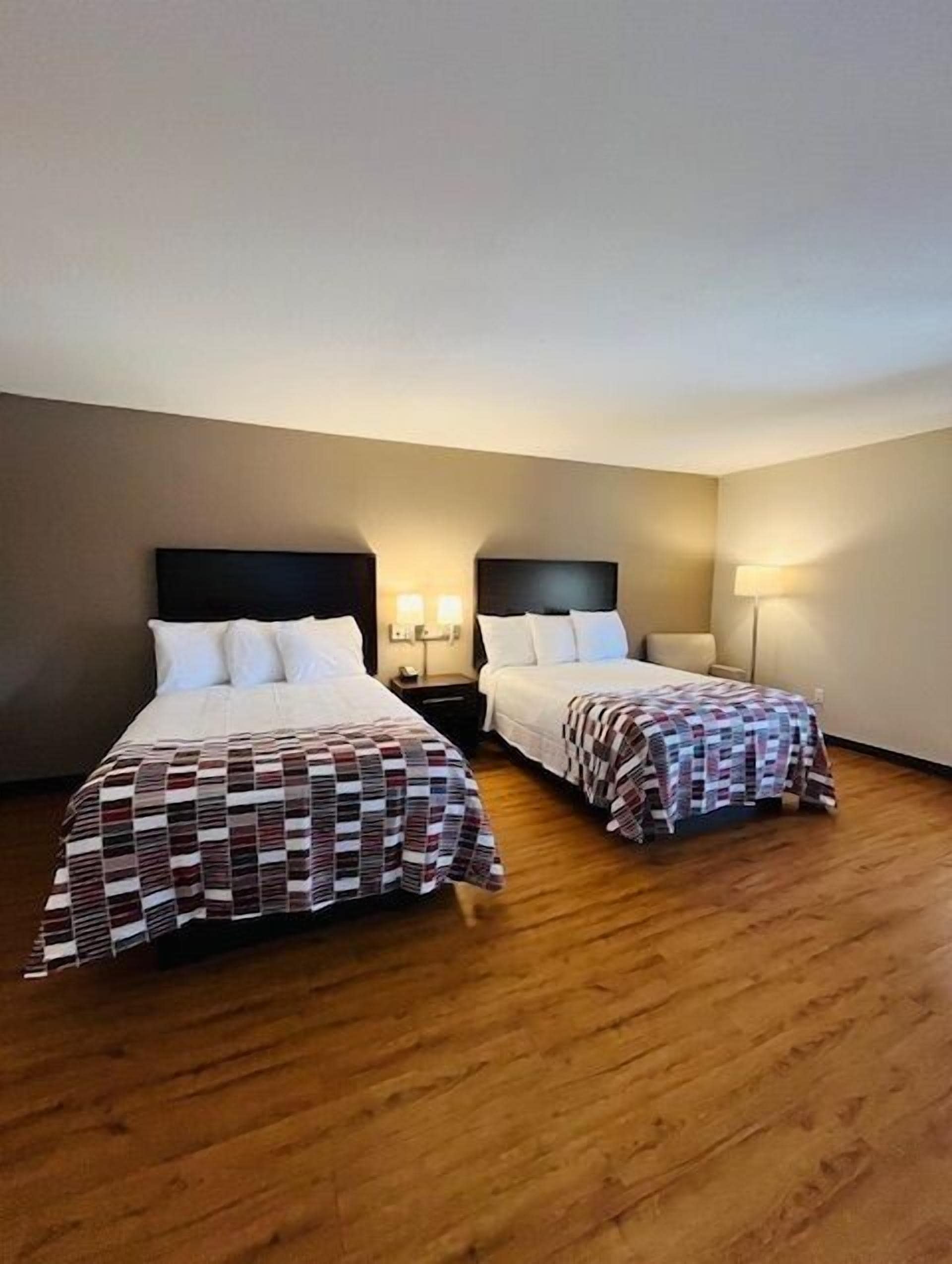 Habitación de hotel con dos camas, piso de madera y una decoración en tonos neutros.