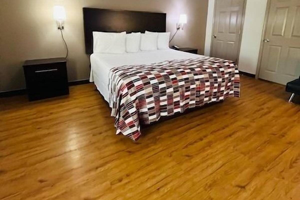Une chambre à coucher avec un lit, un plancher en bois, deux tables de chevet et une tête de lit.