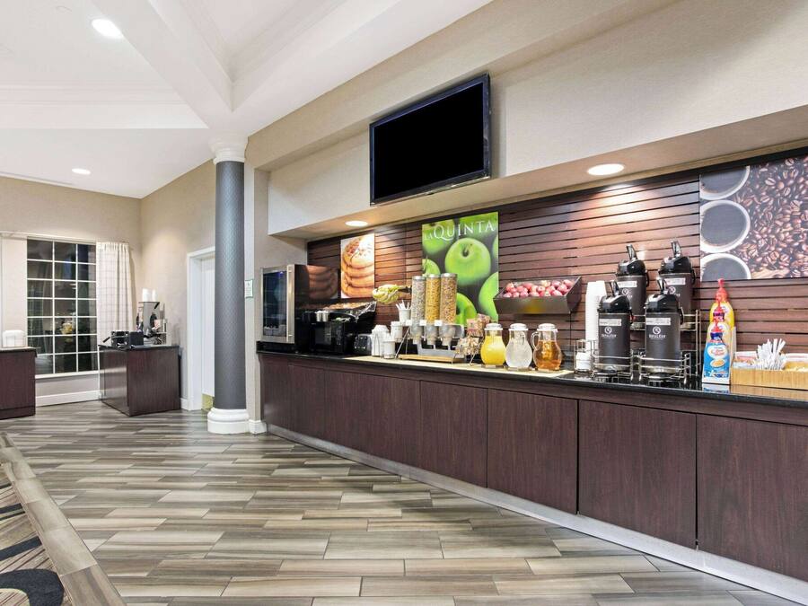 Un hall d’hôtel comprenant un comptoir d’accueil, un grand téléviseur et un espace dédié au café.