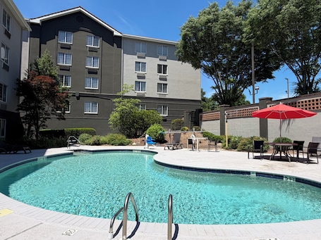A swimming pool with a 3 FT 6 IN depth, surrounded by a patio area with outdoor furniture and a red umbrella.