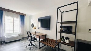 A modern hotel room with a desk, chair, TV, and a shelf unit. - La Quinta Inn & Suites by Wyndham Birmingham Homewood (Birmingham)