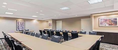 Un salón de conferencias con una larga mesa, sillas y obras enmarcadas en las paredes.