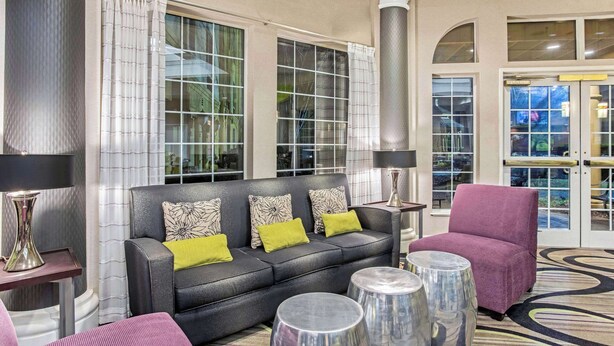 A modern lobby with a black leather sofa, a purple armchair, and a patterned rug. - La Quinta Inn & Suites by Wyndham Birmingham Homewood (Birmingham)