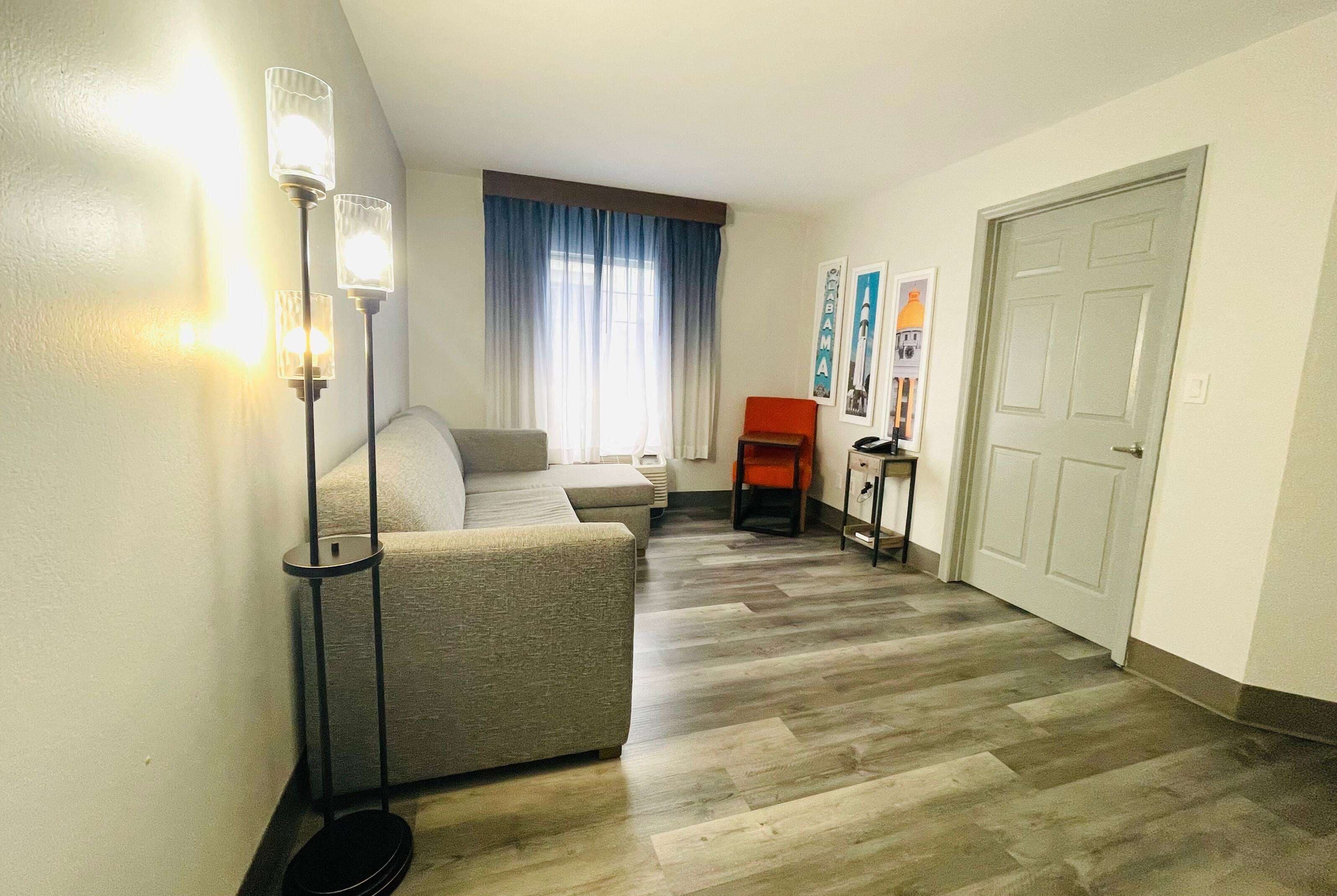 A hallway with a sofa, a floor lamp, a chair, and a door.