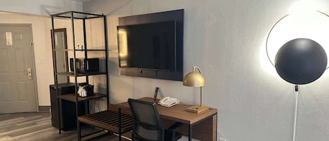 Un espacio de oficina moderno con un escritorio, una silla y un televisor de pantalla plana grande montado en la pared.