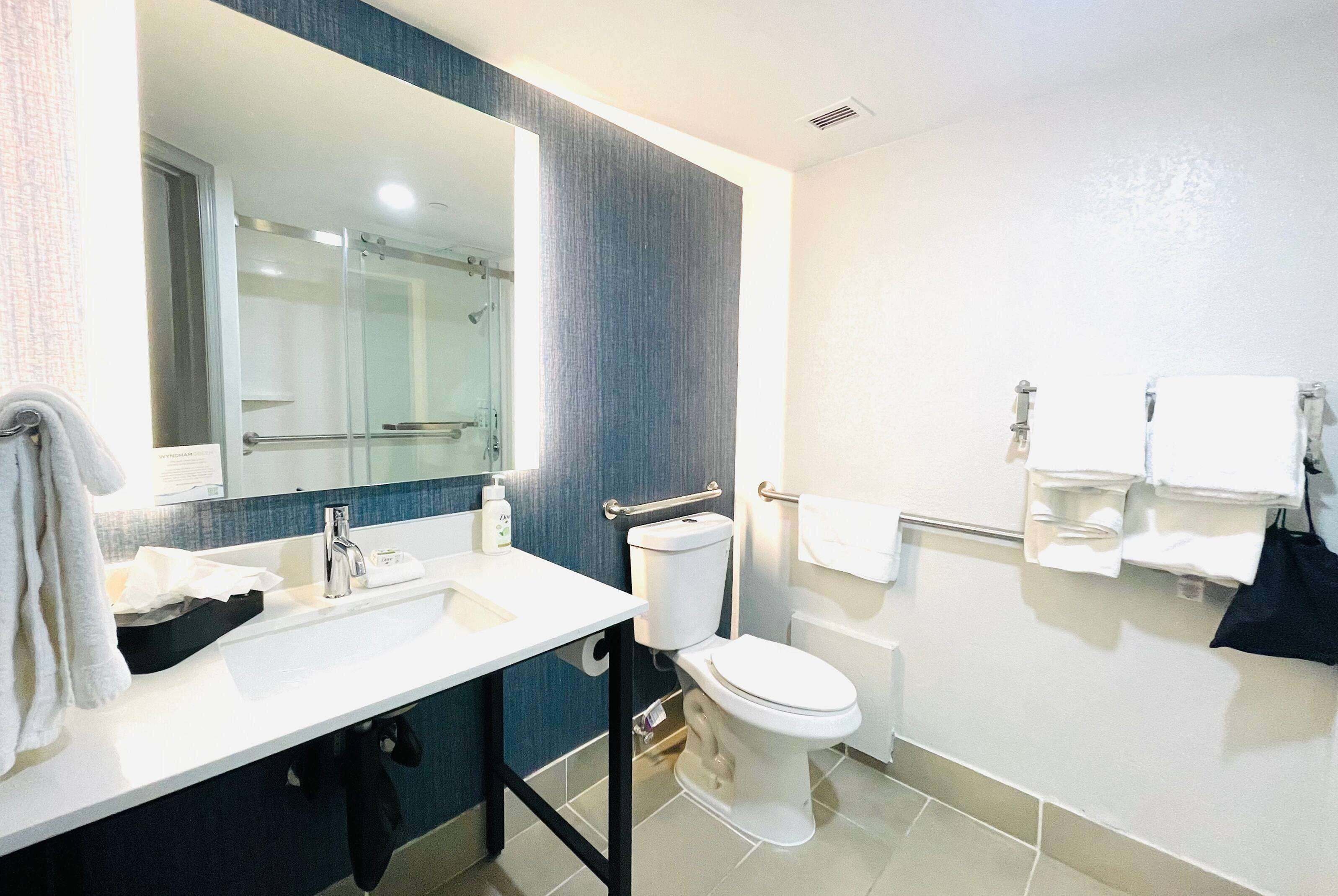 Une salle de bain moderne avec un lavabo blanc, un miroir, des toilettes et un espace douche.