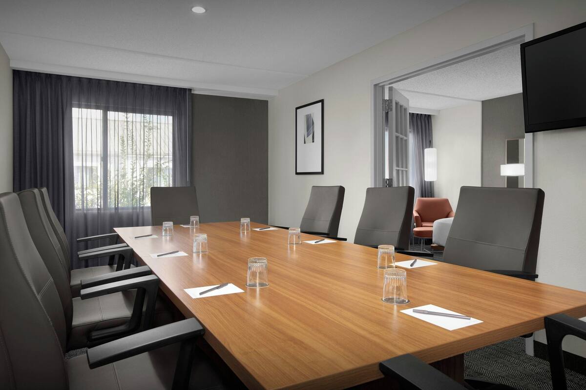 A conference room with a long table, multiple chairs, and a television on the wall.
