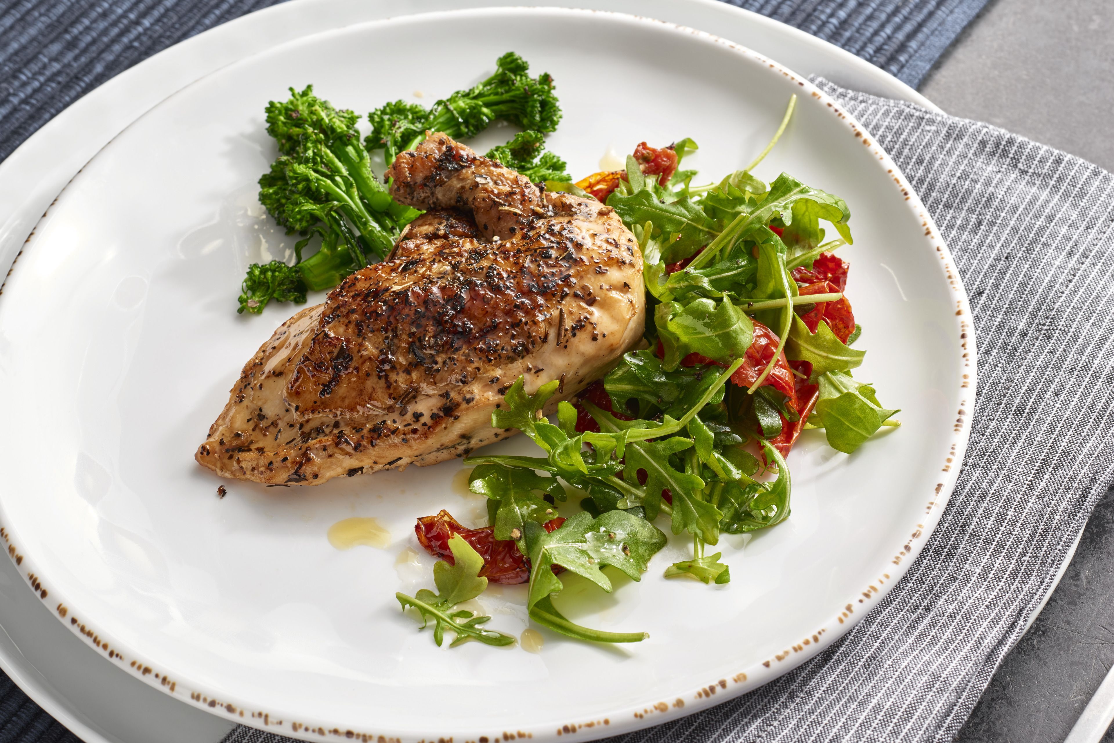 A plate with grilled chicken, broccoli, and a salad.
