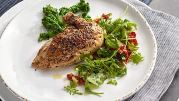 A plate with grilled chicken, broccoli, and a salad.