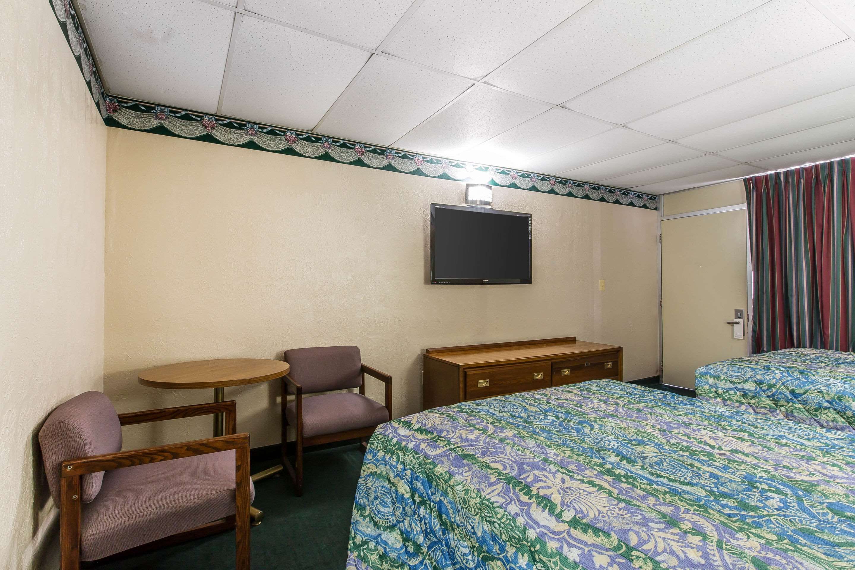 Camera d'albergo con un letto, una scrivania, una sedia, una televisione e una porta con tende.