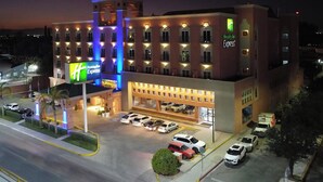 Un hotel Holiday Inn Express con un estacionamiento y varios coches aparcados en la entrada.