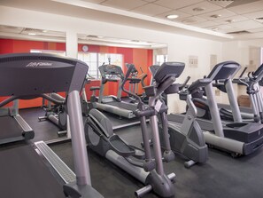 Un gimnasio con varias caminadoras y elípticas.