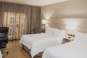Una habitación de hotel con dos camas, una silla, una mesita de noche y una lámpara.