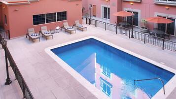 Una piscina al aire libre, sillones reclinables de piscina