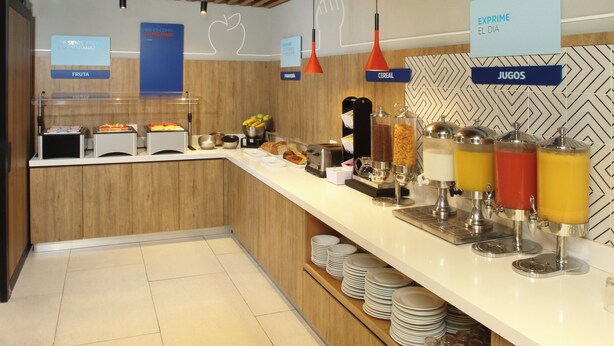 A breakfast bar with fruit, cereal, and juice dispensers. - Holiday Inn Express Torreon by IHG (Torreón)