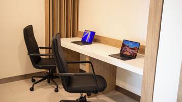 Ein Arbeitsplatz mit zwei schwarzen Bürostühlen, einem weißen Schreibtisch und zwei Laptops.