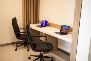 Un espacio de trabajo con dos sillas de oficina negras, un escritorio blanco y dos computadoras portátiles.