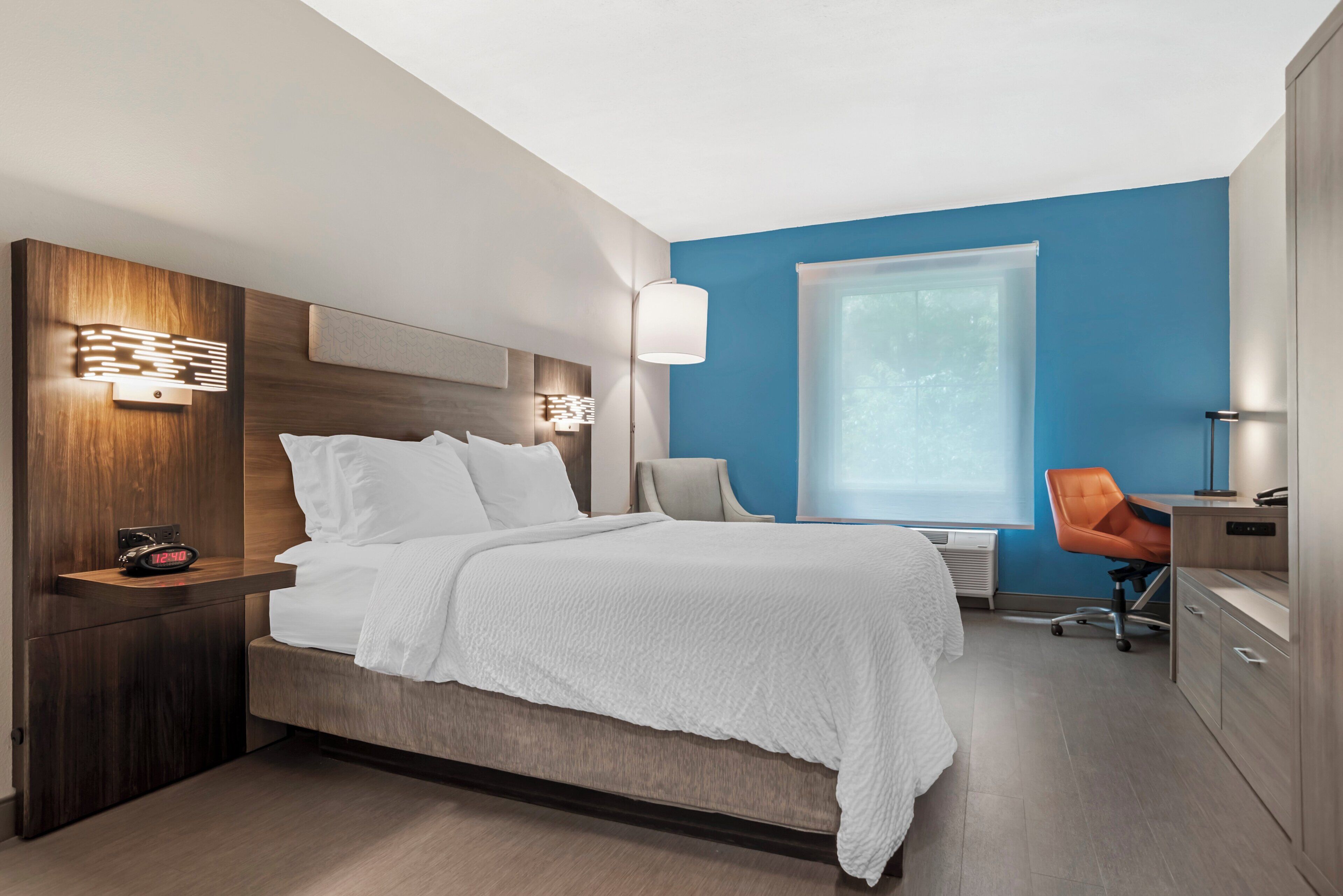 Ein modernes Hotelzimmer mit einem großen Bett, Nachttischen, einem Schreibtisch und einem Stuhl.