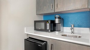 A kitchenette with a microwave, coffee maker, and a sink.