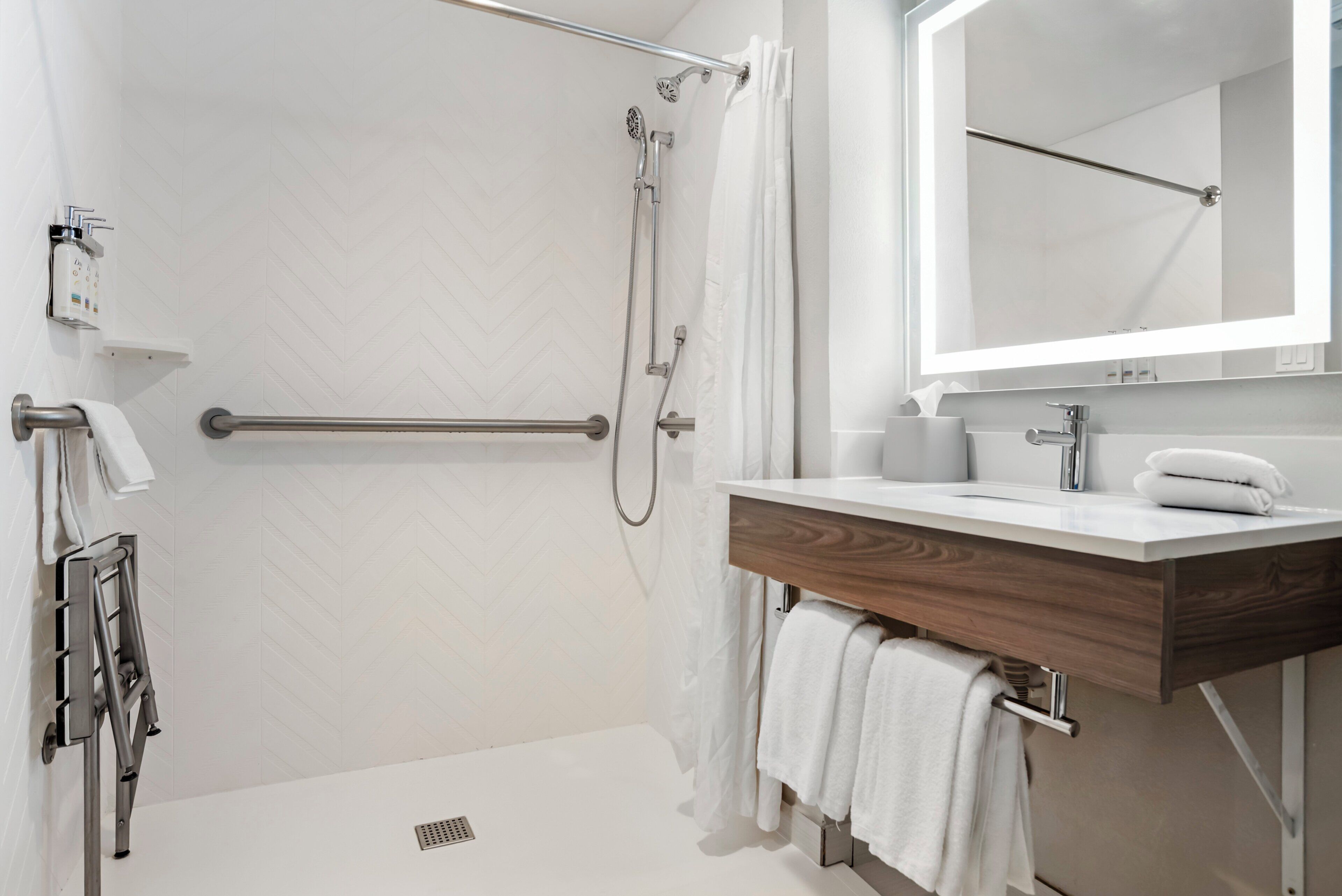 Un baño moderno con ducha, inodoro, lavabo con espejo y toallero.