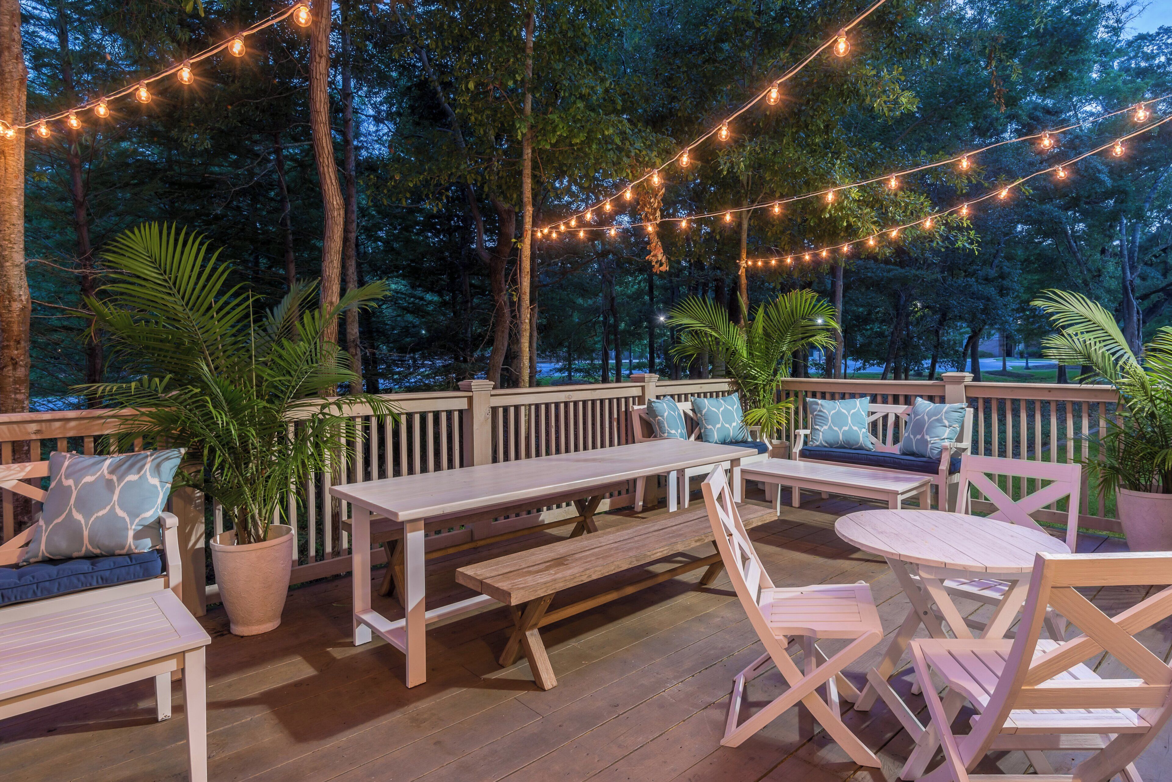 An outdoor deck with wooden furniture, string lights, and potted plants.