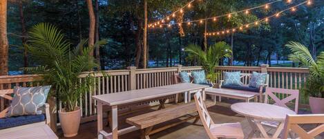 An outdoor deck with wooden furniture, string lights, and potted plants.