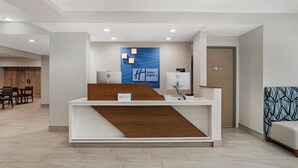 A hotel reception desk with a blue wall art, a wooden counter, and a sign indicating 'Holiday Inn Express.' - Holiday Inn Express Fairhope by IHG (Fairhope)