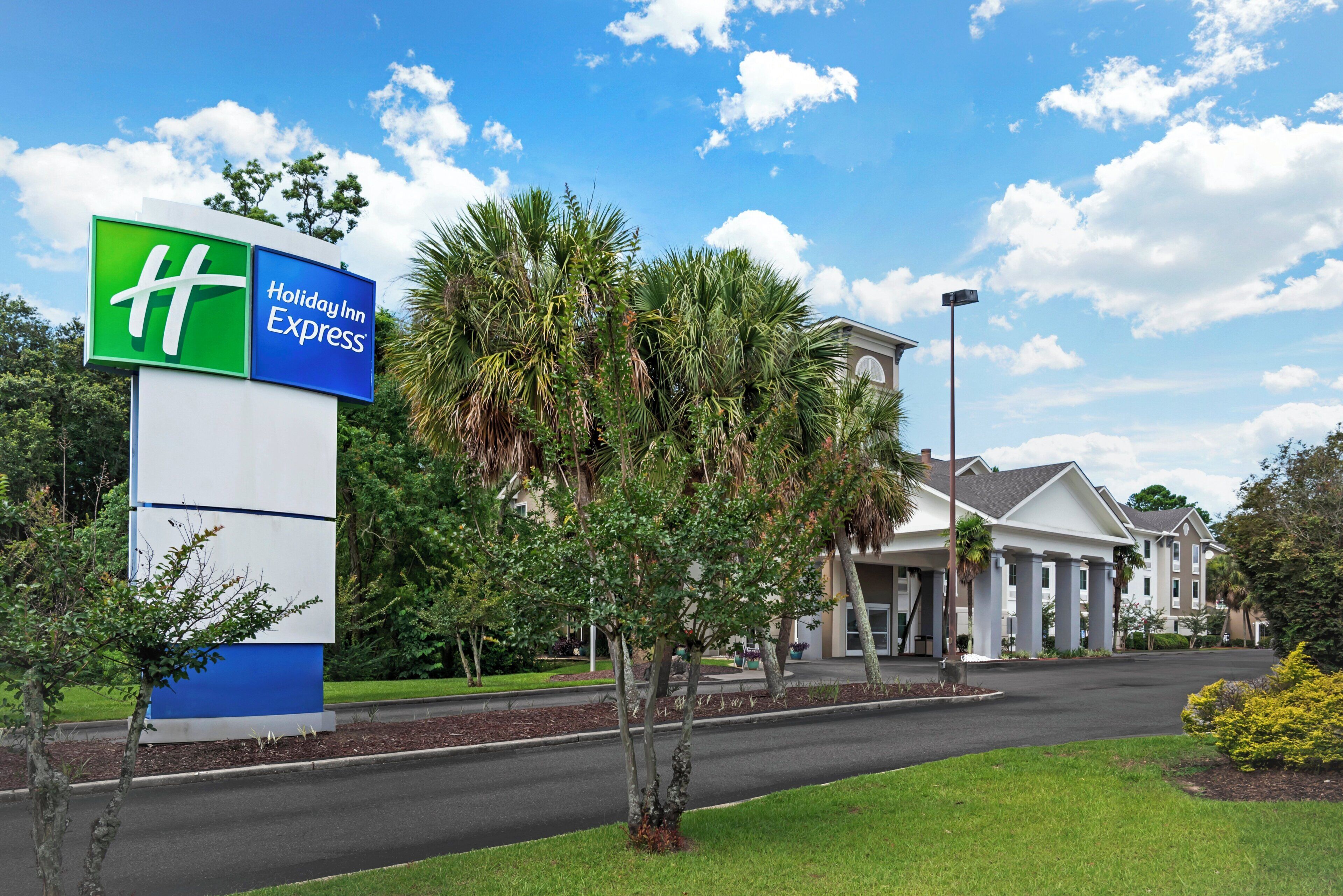 A Holiday Inn Express sign, a building with a modern design, and a well-maintained lawn.