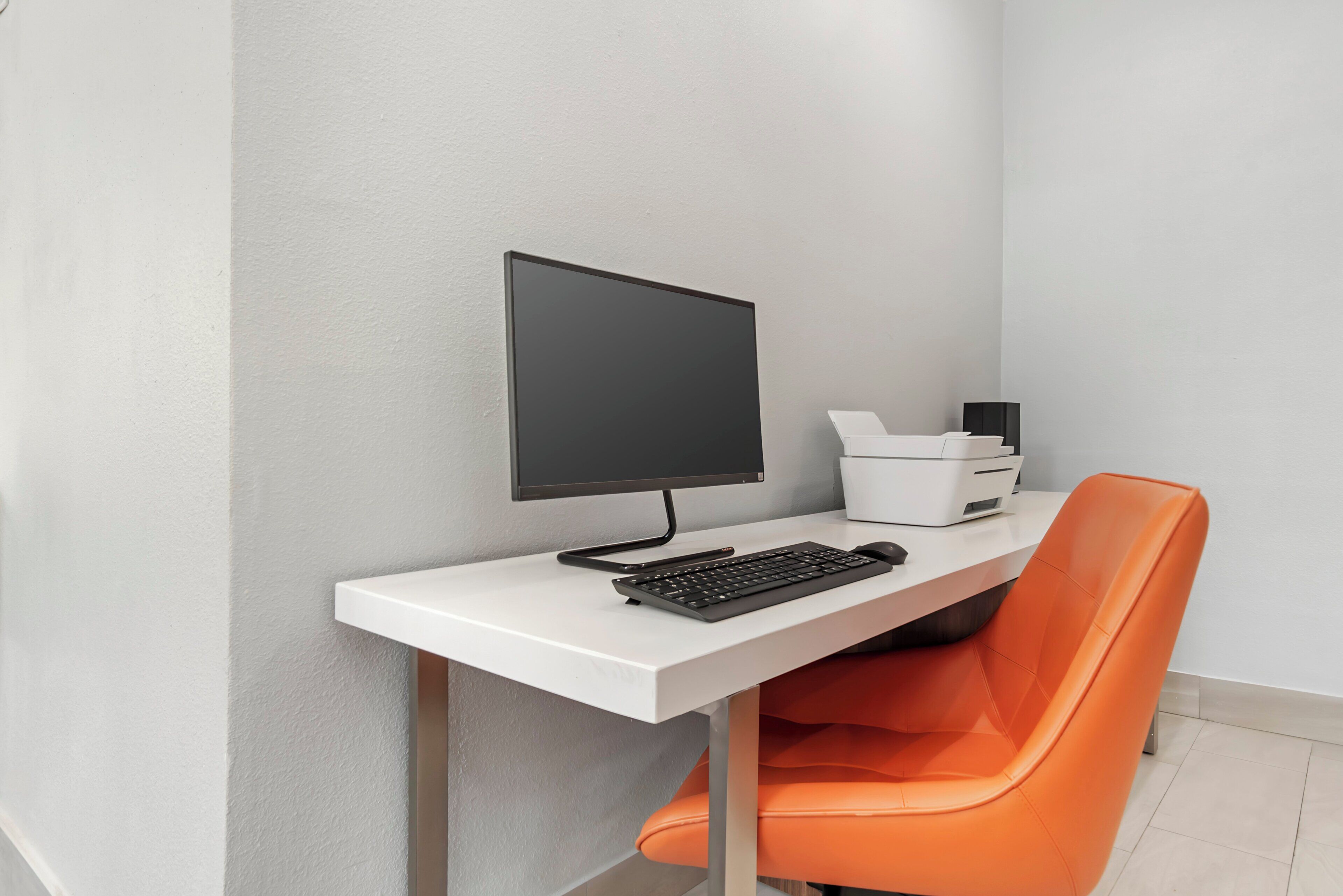 A modern office desk with a computer, keyboard, and printer.
