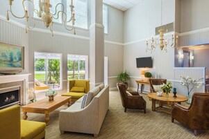 A spacious living room with a fireplace, comfortable seating, a television, and a large window offering a view of the outdoors.