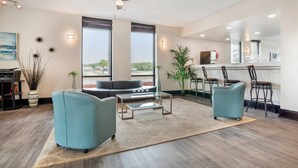 A modern living room with a sofa, two armchairs, a coffee table, and a dining area with bar stools.