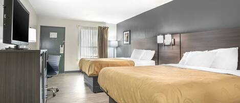 A hotel room with two beds, a desk with a flat-screen TV, a chair, and a door.