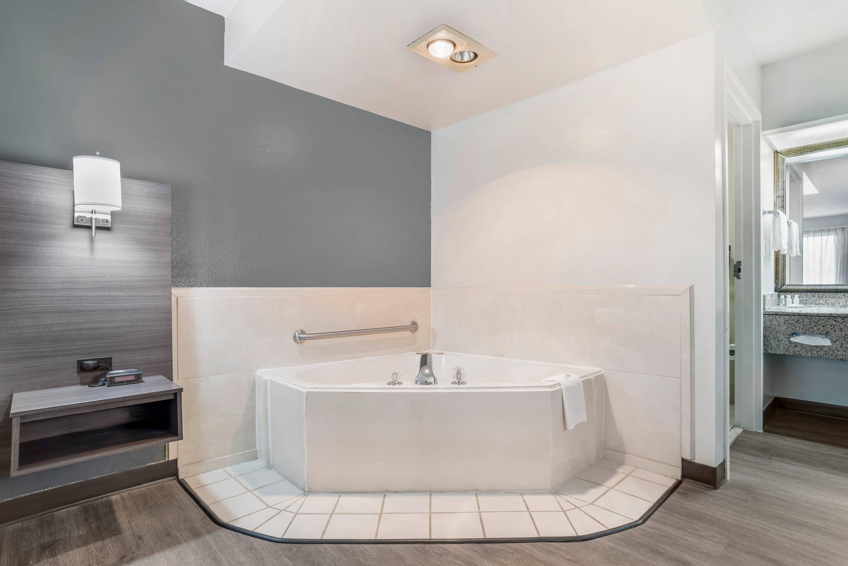 A modern bathroom with a freestanding bathtub, a towel rack, and a wall-mounted light fixture.