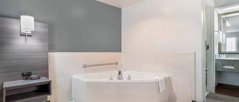 A modern bathroom with a freestanding bathtub, a towel rack, and a wall-mounted light fixture.