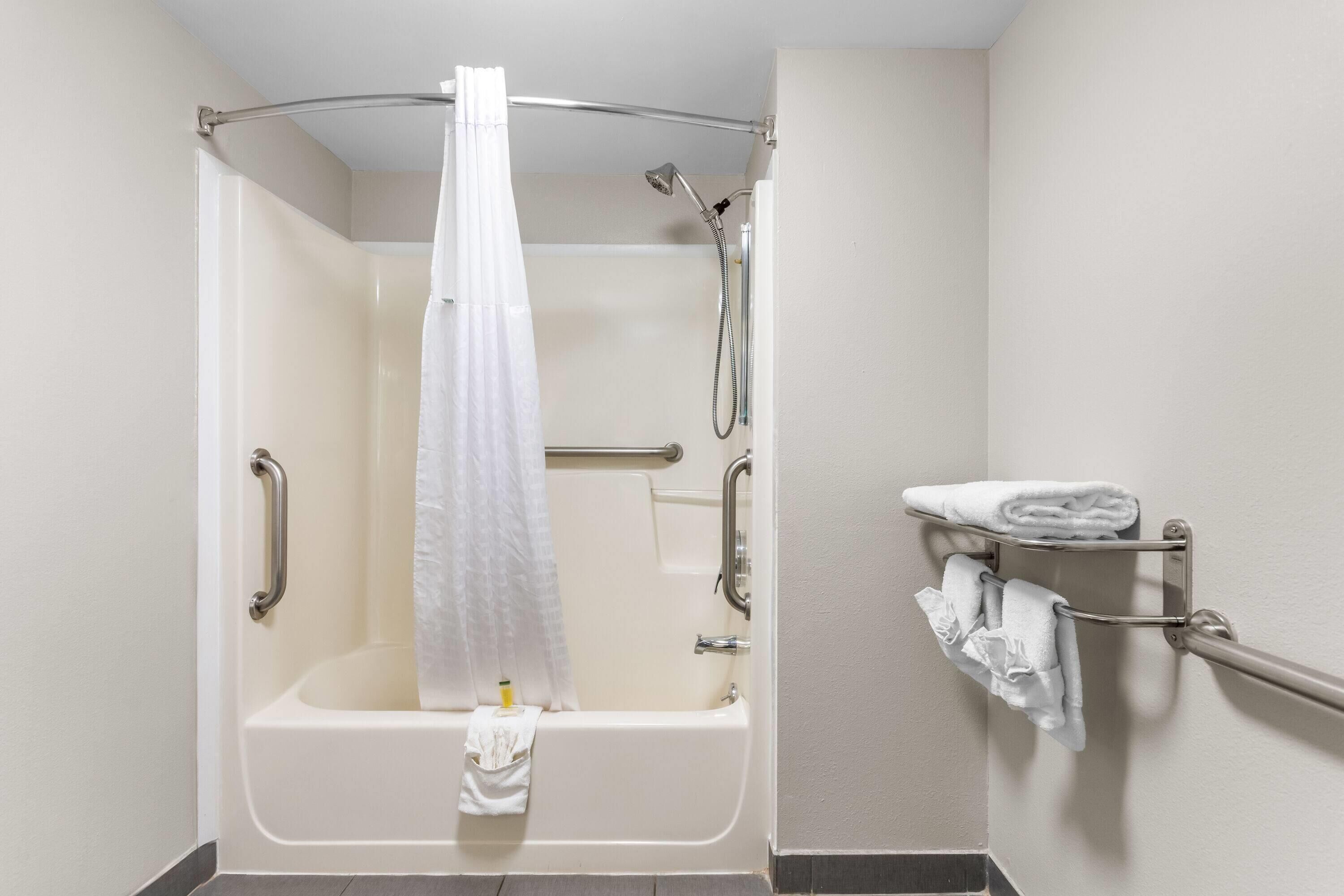 A walk-in shower with a grab bar, a towel rack, and a showerhead.