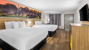 A hotel room with two beds, a TV, a painting of a sunset, and a wooden desk. - Days Inn by Wyndham Enterprise (Enterprise)