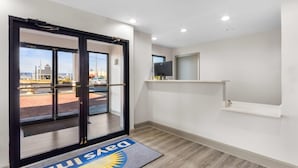 A hotel entrance with a sliding glass door, a reception desk, and a view of the outside. - Days Inn by Wyndham Enterprise (Enterprise)