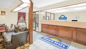 A Days Inn reception area with a leather sofa, a reception desk, and a clock on the wall. - Days Inn by Wyndham Eufaula AL (Eufaula)