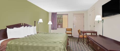 A hotel room with a bed, a desk, a chair, a television, and a window with curtains.