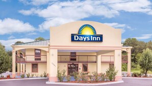 A Days Inn building with a prominent sun logo, a two-story structure, and a covered front porch. - Days Inn by Wyndham Eufaula AL (Eufaula)