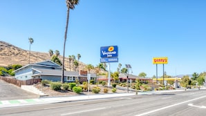 Una carretera con un letrero azul para Vagabond Inn y un letrero amarillo para Denny's.