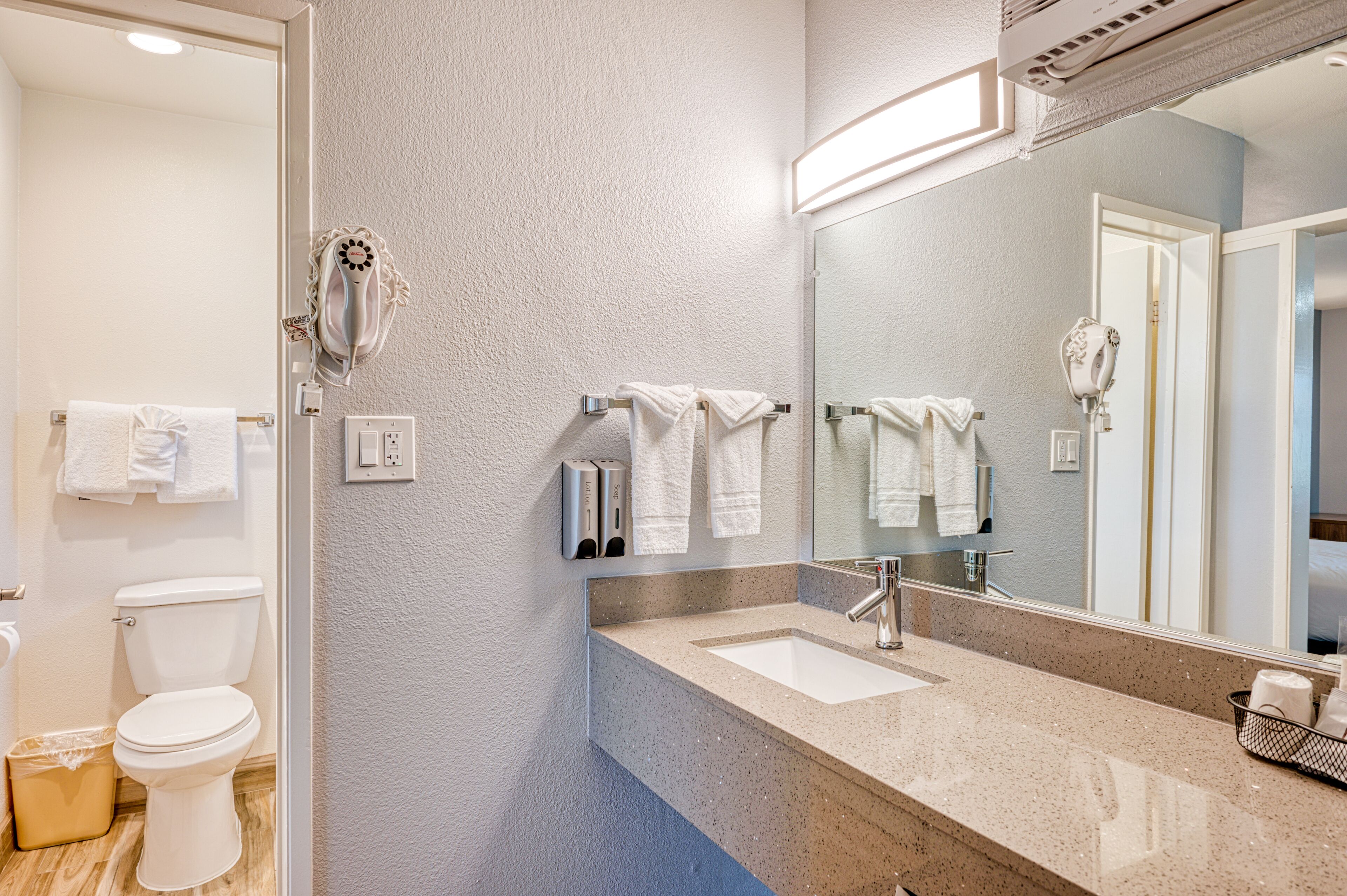 A bathroom with a sink, mirror, towel rack, and toilet.