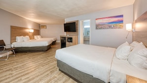 Una habitación de hotel con dos camas, un escritorio, un televisor y un cuadro en la pared.