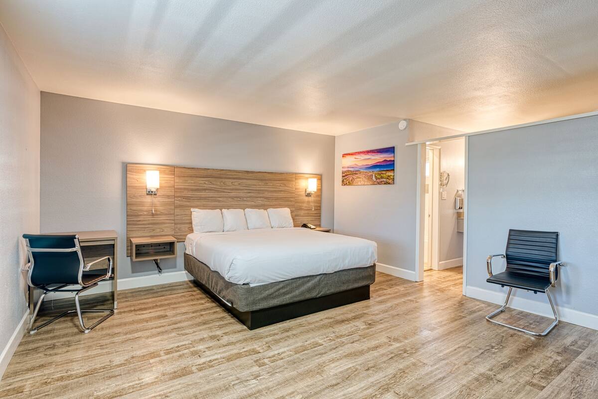 Une chambre d’hôtel moderne, dotée d’un grand lit, d’un bureau et d’une chaise.