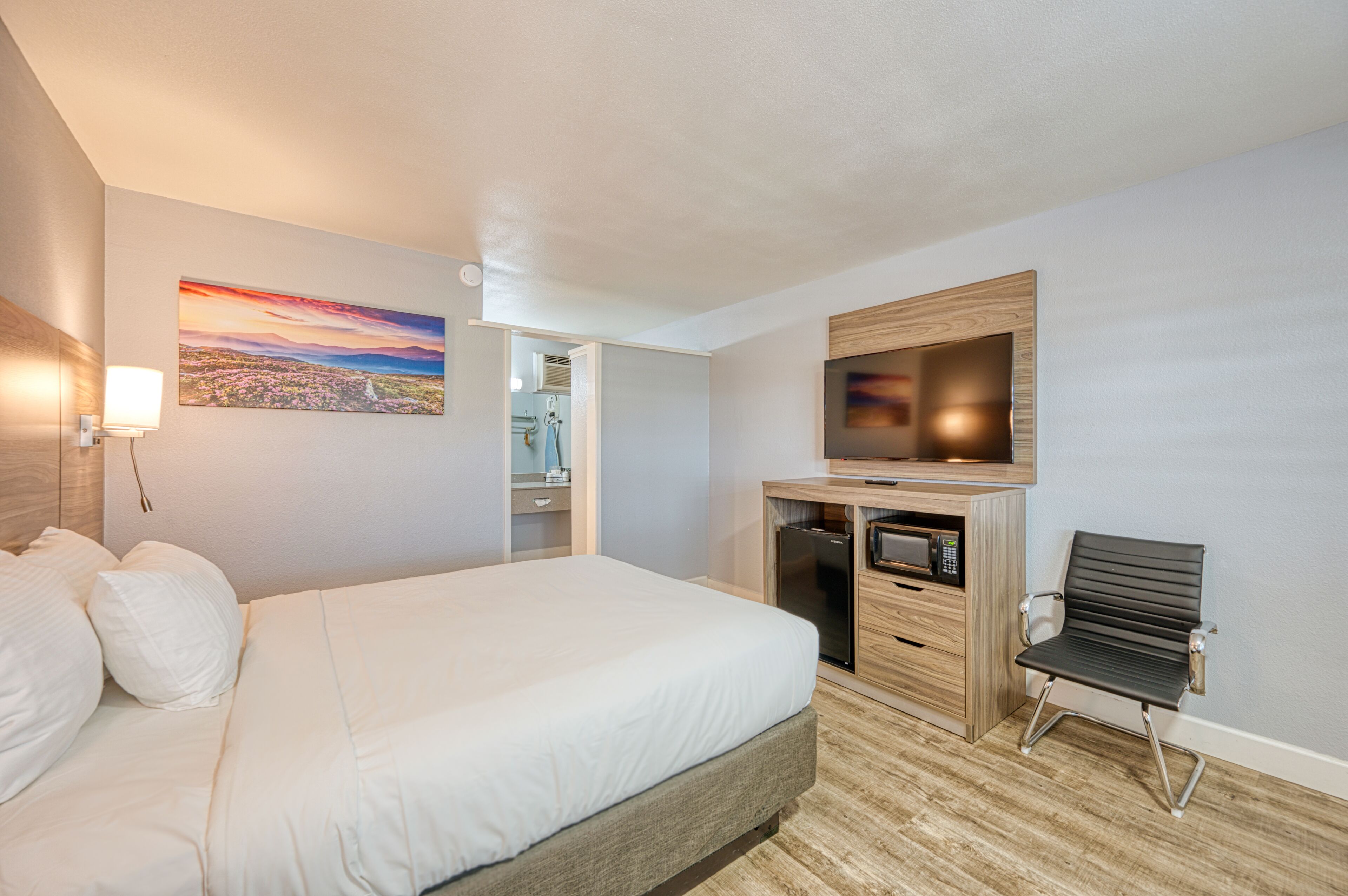 Una camera d'hotel con un letto, una scrivania con un computer, una televisione e una sedia.