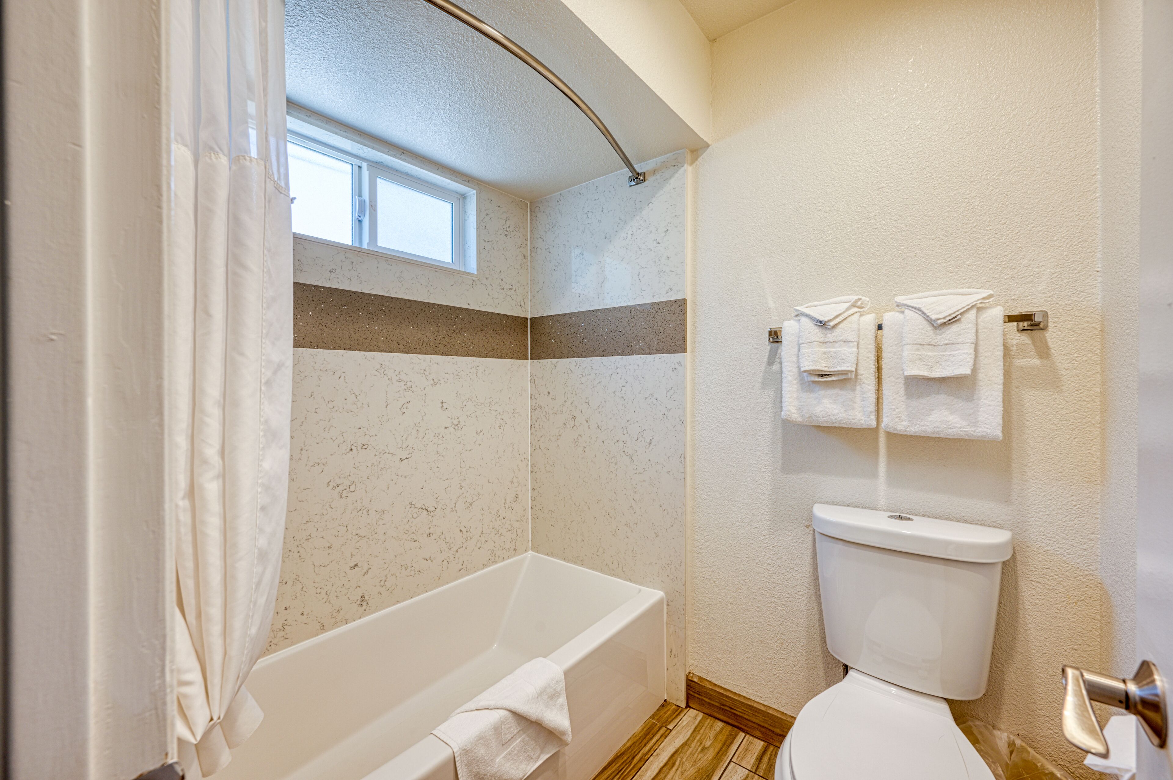 Een badkamer met een bad, toilet en handdoekhouder.