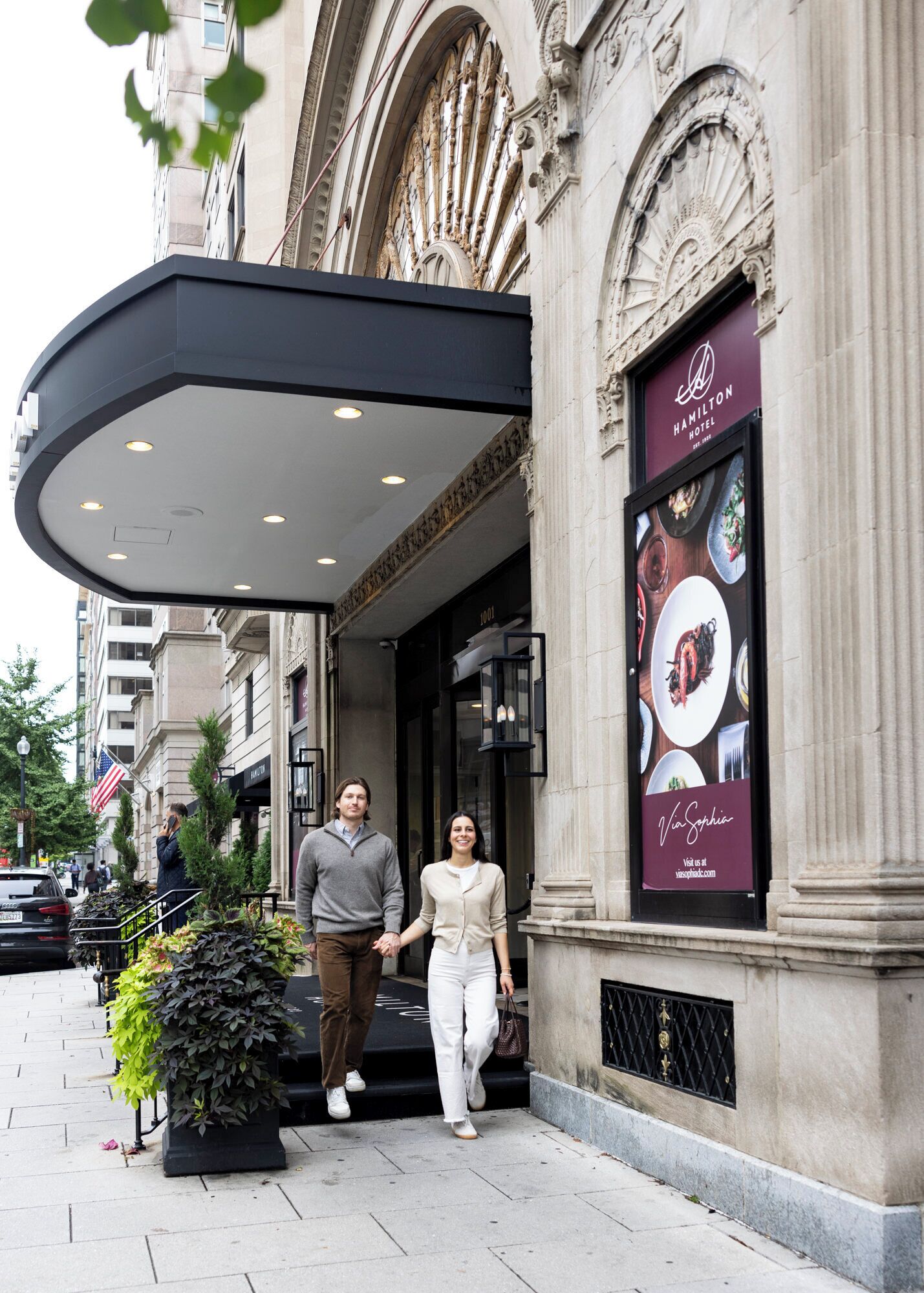 A hotel entrance with a classic architectural facade, a covered entrance area, and a sign advertising the hotel's name and amenities.