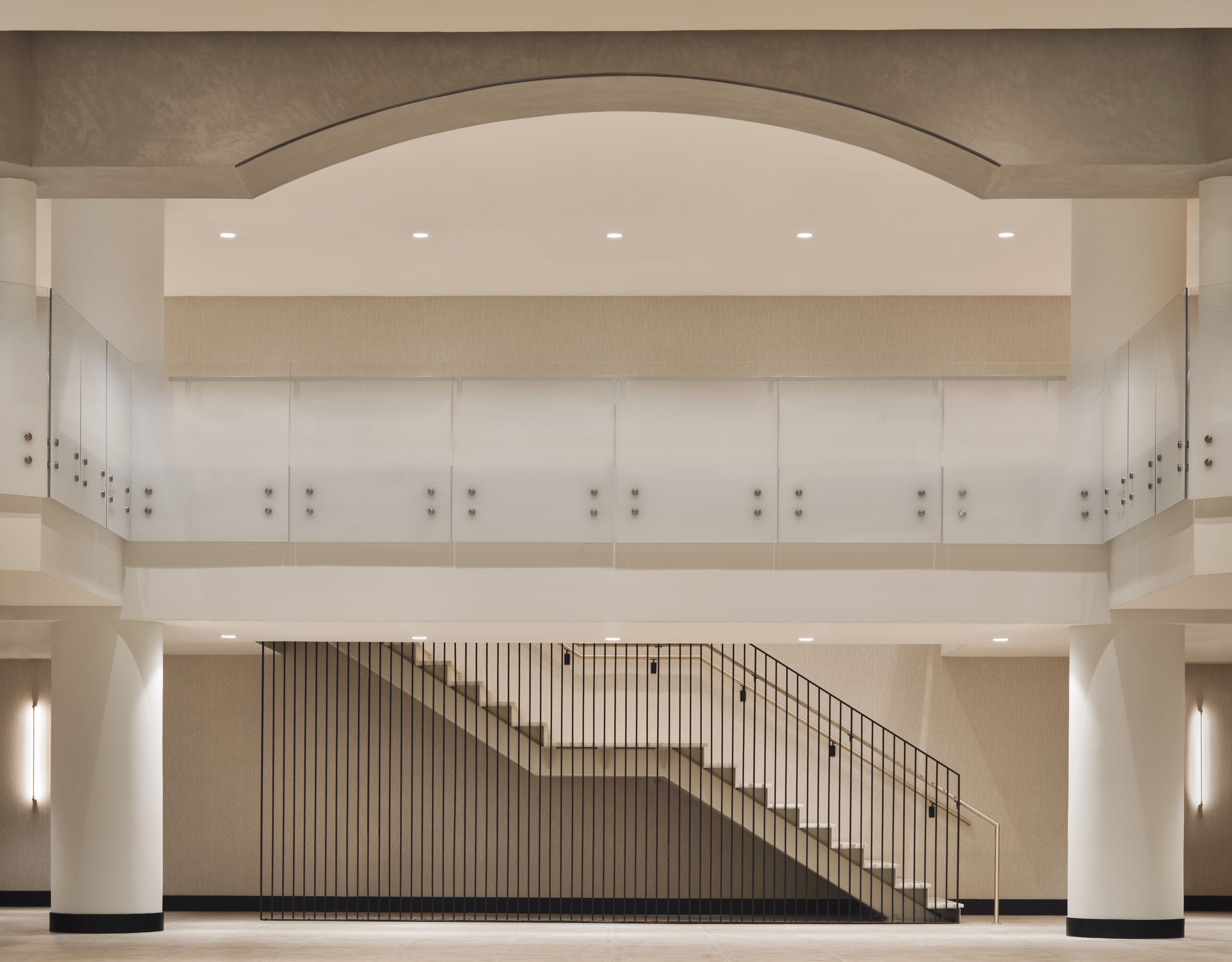 A spacious interior with a central staircase, high ceilings, and a modern design.