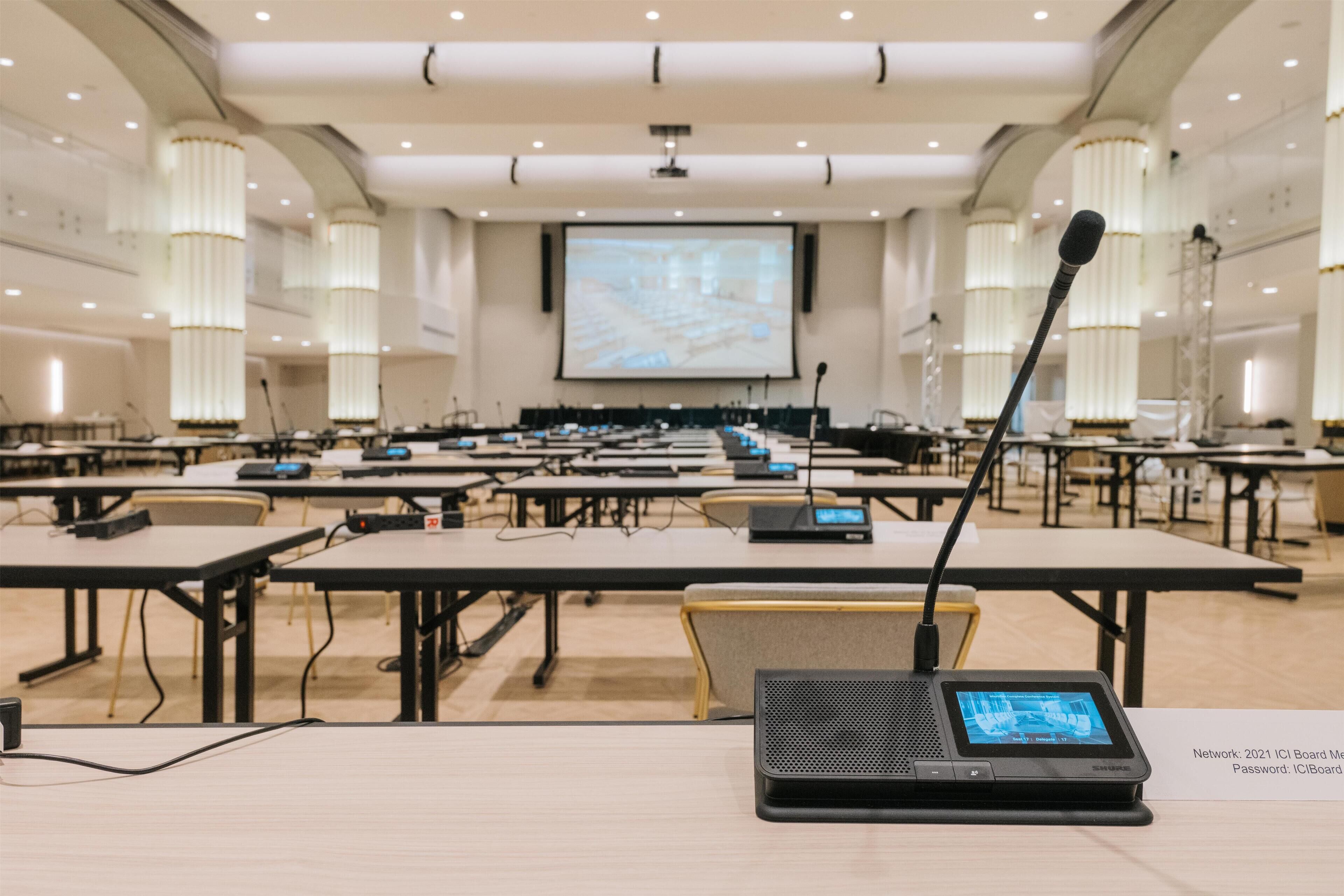 Une salle de conférence équipée de tables, d’ordinateurs portables et d’un écran de présentation.