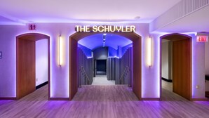 Un passadís amb 'THE SCHUYLER' il·luminat al final, sòl de fusta i il·luminació moderna.